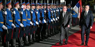 Zwei Männer schreiten eine Militärparade ab.