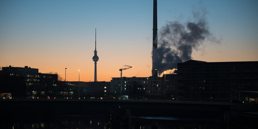 Im Morgengrauen steigt Dampf von einem Heizkraftwerk auf. Im HIntergrund ist der Fernsehturm zu sehen