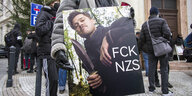 Eine Person hält ein Plakat, auf dem Brad Pitt und die Aufschrift "FCK NZS" zu sehen ist