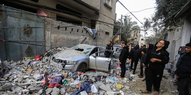 Menschen in Gaza blicken auf Trümmer vor einem Haus in der Stadt Rafah im Gazastreifen