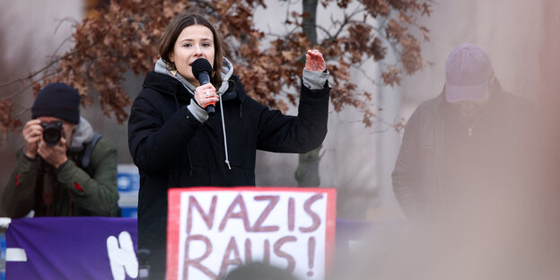 Luisa Neubauer spricht in ein Mikrofon, vor ihr ist ein Plakat auf dem ist "Nazis Raus" zu lesen