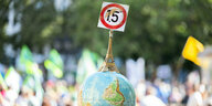 Einen Globus mit einem Miniatur-Eiffelturm und dem 1,5-Grad Ziel des Pariser Klimaschutzabkommens trägt ein Mann auf der Demonstration