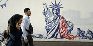 Menschen gehen an einem staatlich organisierten, US-amerikafeindlichen Wandgemälde an der Wand der ehemaligen US-Botschaft vorbei