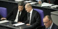 Habeck und Scholz tuscheln, während Merz im Bundestag spricht