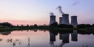 Vier Reaktoren sind im Hintergund vor einem Gewässer zu sehen, vor Sonnenuntergang