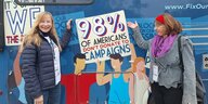Zwei Frauen stehen vor einem blauen Wahlkampfbus und zeigen auf Werbeschriften für Nikki Haley