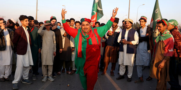 Menschen, einer von ihnen in den Farben der PTI, tanzen auf der Straße