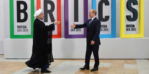 Der iranische Präsident Hassan Rouhani (l) und Wladimir Putin laufen aufeinander zu