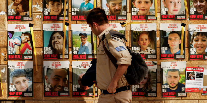 Ein israelischer Soldat läuft an Postern der Geiseln entlang .