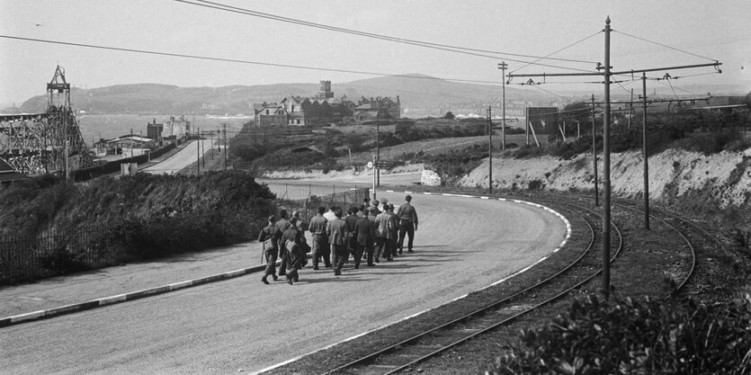 Historisches Foto einer Menschenkolonne auf einer Straße.