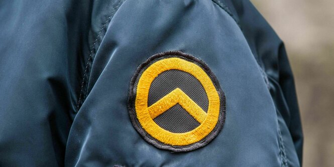 Logo der identitären Bewegung - ein gelber Kreis mit einem nach oben gerichteten zweischenkligen Dreieck