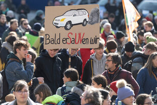 Menschen auf einer Demonstration: „Bald erSaUVen wir“ steht in Anspielung auf SUV-Fahrzeuge