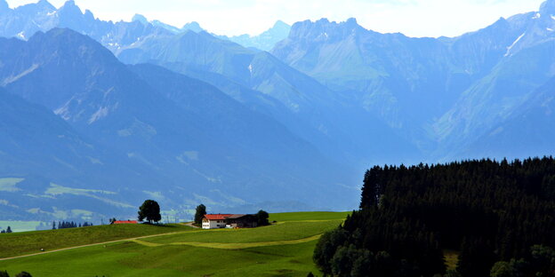 Ein Bauernhof vor einem Alpenpanorama