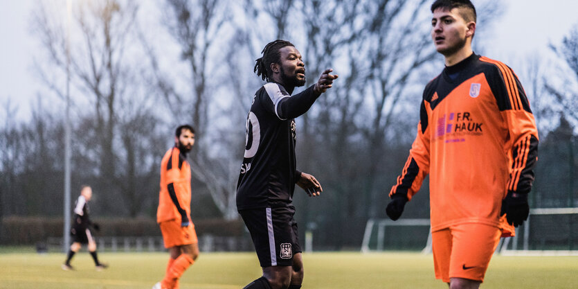 Fußballer der Afrisko stehen auf dem Fußballfeld. Zu sehen sind drei Fußballspieler.