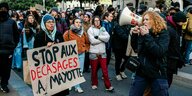 Eine Gruppe junger Leute demonstriert, eine Frau trägt ein Plakat mit der Aufschrift: Stop aux Decasages a Mayotte - damit soll das Einbürgerungsrecht ausgehelbelt werden