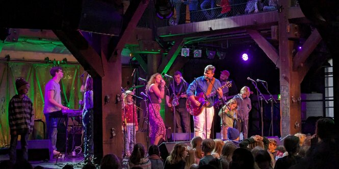 Bernd Begemann steht mit anderen Musikern und Musikerinnen auf der Bühne der Fabrik in Hamburg.