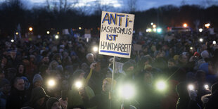 Proteste mit Lichtern und einem Schild.