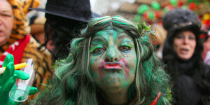 Eine Karnevalistin mit grüner Perrücke macht einen Kußmund.