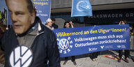 Demonstrant*innen vor Banner: "Völkermord der Uiguren. VW muss sich zurückziehen"