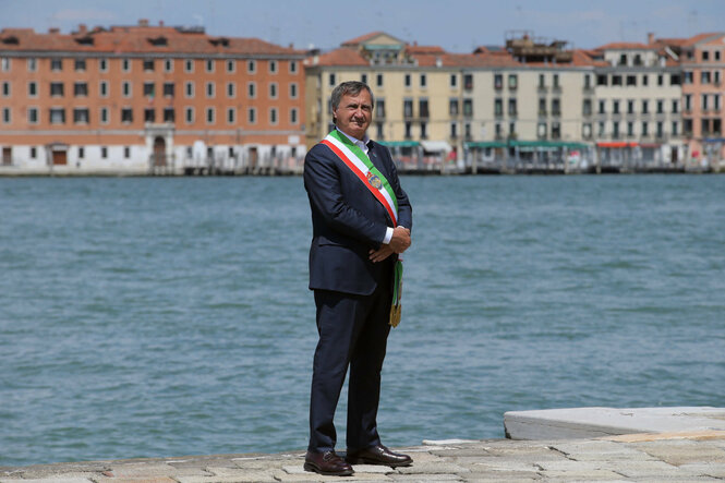 Ein Mann steht vor der Venedigs Stadtsilhouette.