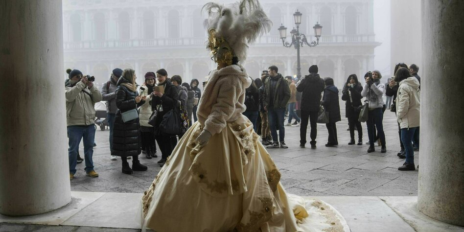 Viele Menschen stehen vor einer kostümierten Frau in Venedig.