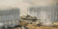 Ein israelischer Panzer fährt durch ein Loch in einem Zaun.