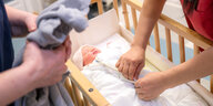 Eine Pflegekraft am St.-Joseph-Stift in Bremen kümmert sich um ein Neugeborenes und knüpft dessen Schlafsack zu