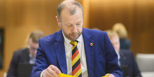 AfD-Fraktionsvorsitzender Stefan Marzischewski-Drewes sitzt mit einer Krawatte in schwarz-rot-gold im Niedersächsischen Landtag.