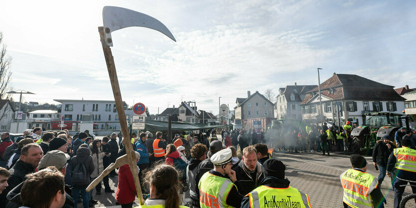 Polizei und Demonstrierende mit einer Sense