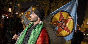 Demonstrant mit Pali-Fahne um den Hals und Young Struggle-Fahne