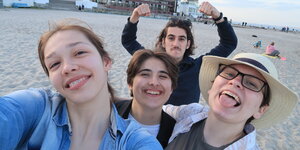 4 junge Menschen blödeln an einem Strand beim Selfie