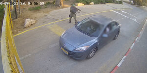 Bild einer Überwachungskamera zeigt: Bewaffneter ziehlt auf eine Person in einem Auto.