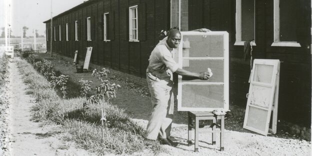 Ein namenloser Schwarzer Häftling putzt ein Fenster im KZ Neuengamme