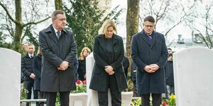 Die Politiker:innen Claus Kaminsky, Nancy Faeser und Boris Rhein auf einem Friedhof.