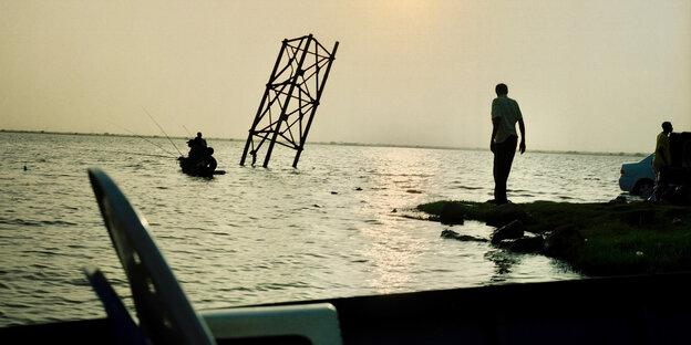 Ein Mann steht am Ufer des Meeres, darin ein Stahlträger