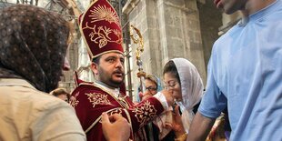 Ein Bischof in einer Kirche, umringt von Menschen