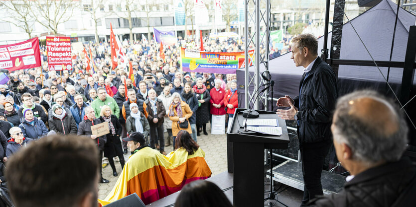 Personen auf der Bühne vor einer Menschenmenge.