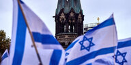 Israel Fahnen auf dem Kurfürstendamm in Berlin und die Kaiser-Wilhelm-Gedächtniskirche im Hintergrund.