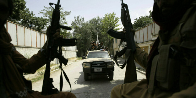 Taliban-Kämpfer sitzen bewaffnet auf einem PickUp - hinter ihnen fährt ein weiteres Auto mit Taliban-Kämpfern