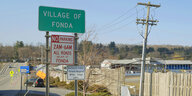 Eine Ansammlung von Schildern an einer Straße, "Village of Fonda" steht auf einem