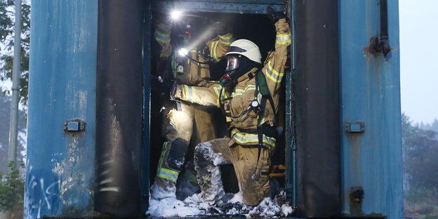 Zwei Feuerwehrleute drängen sich in das brennende Zugabteil