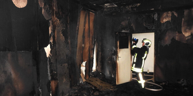 Ein Mitarbeiter der Feuerwehr begutachtet das ausgebrannte Gebäude