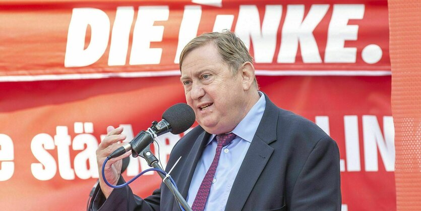 André Hahn bei einer Wahlkampfveranstaltung, er spricht in ein Mikrofon, hinter ihm ein Banner der Partei: Die Linke