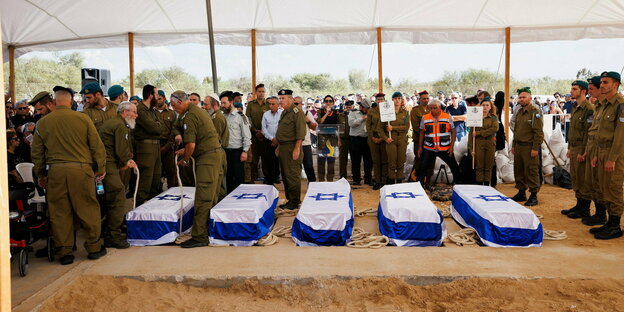 Trauernde Angehörige und Freunde und israelische Soldaten in Uniform, stehen vor Särgen, die mit der israelischen Flagge bedeckt sind