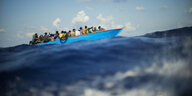 Hoher Wellengang: Migranten sitzen in einem Holzboot im Mittelmeer