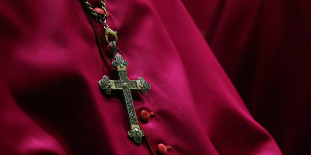 Ein Bischof in roter Kleidung, zu sehen ist nur das Kreuz auf seiner Soutane