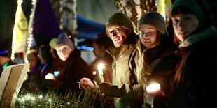 Menschen stehen mit Kerzen bei einer Protestveranstaltung