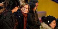 Isabelle Huppert sitzt auf einer Tribüne und spricht mit einer Frau, die nur seitlich zu sehen ist