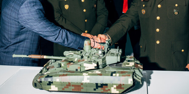 Neben dem Modell eines Panzers werden Hände geschüttelt: am Stand des ukrainischen Rüstungs-Staatskonzerns UkrOboronProm, Lima 2019