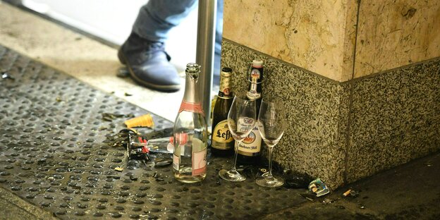 Leere und kaputte Flaschen und Gläser stehen an einer Straßenecke auf dem Boden